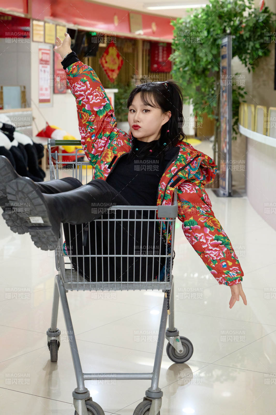 坐在商場(chǎng)超市購(gòu)物車拍照玩樂(lè)的亞洲美女