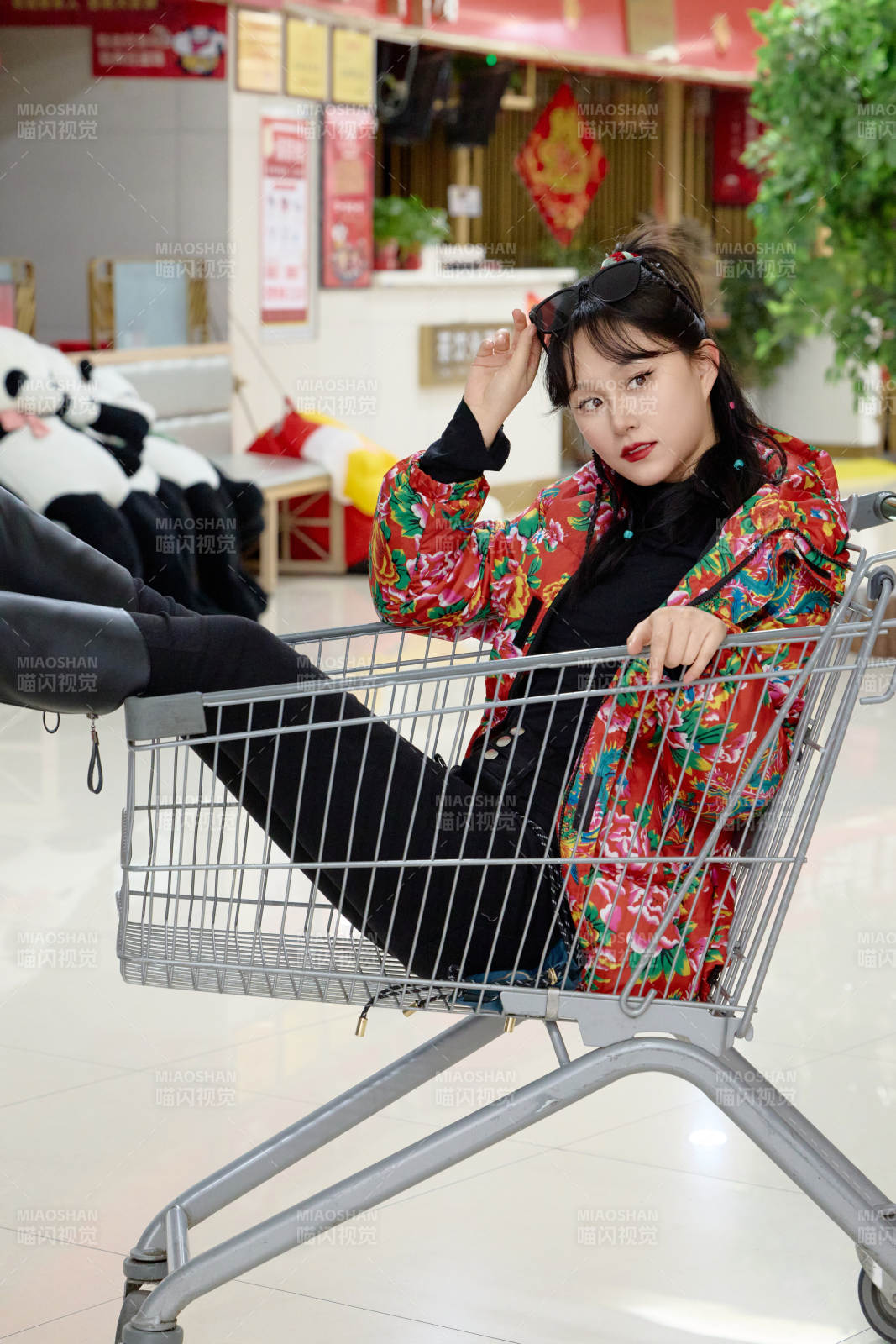 坐在商场超市购物车拍照玩乐的亚洲美女