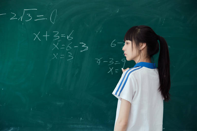 上课时在教室黑板解答数学习题的高中生