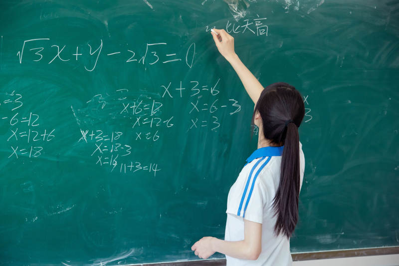 上课时在教室黑板解答数学习题的高中生