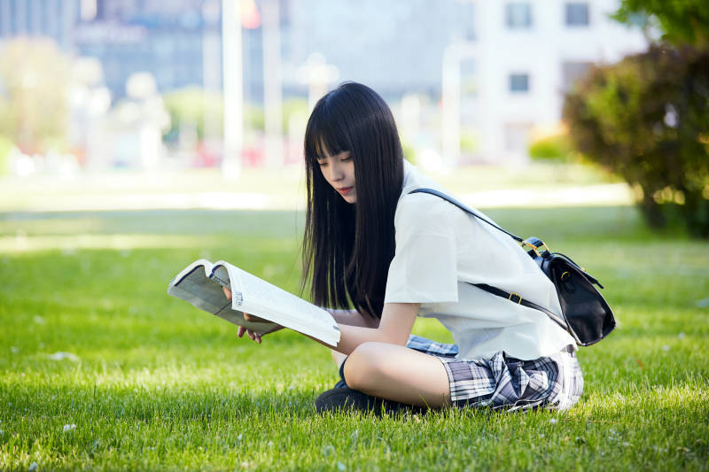 在户外草坪看书学习的女生