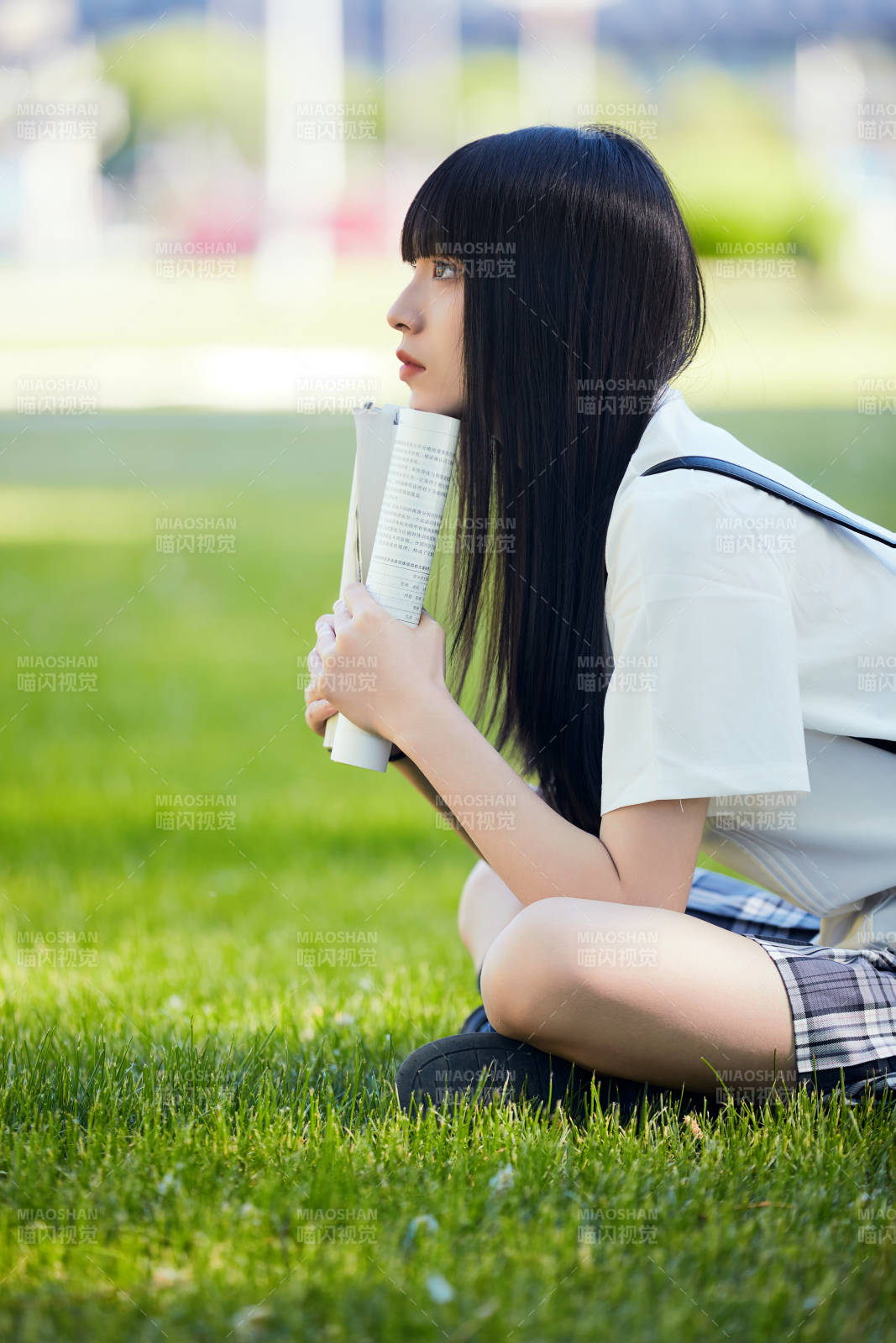 在戶外草坪看書學(xué)習(xí)的女生