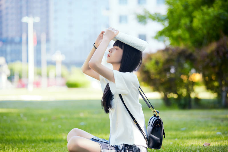 在户外草坪看书学习的女生