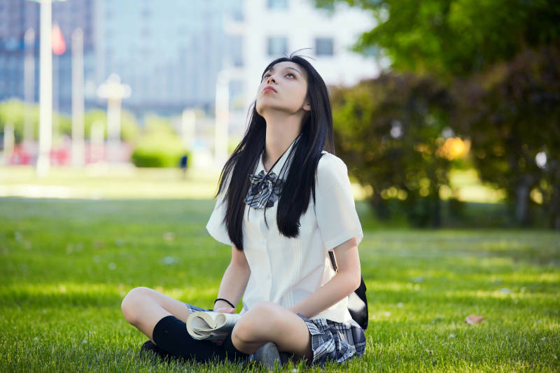 在户外草坪看书学习的女生