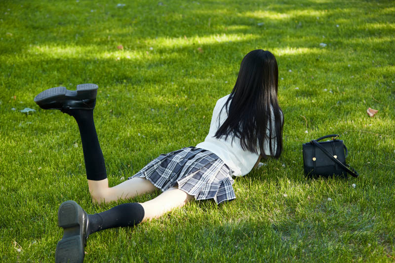 在户外草坪看书学习的女生