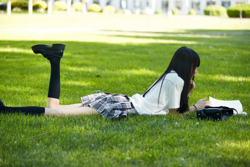 在户外草坪看书学习的女生