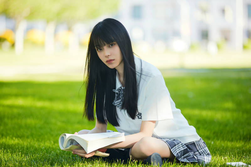 在户外草坪看书学习的女生