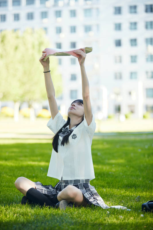 在户外草坪看书学习的女生