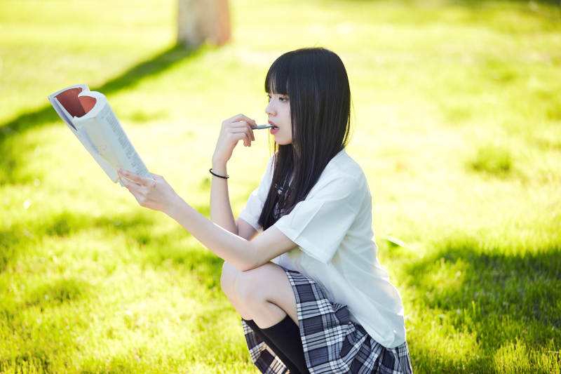 在户外草坪看书学习的女生