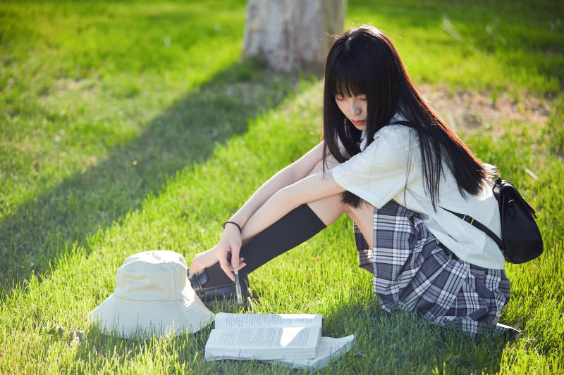 在户外草坪看书学习的女生