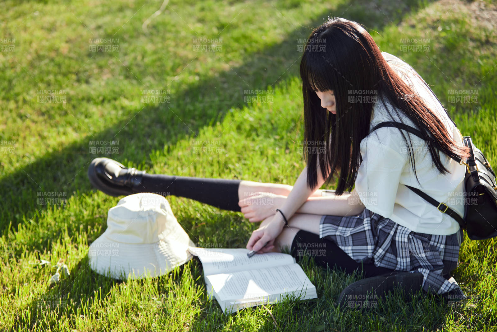 在户外草坪看书学习的女生