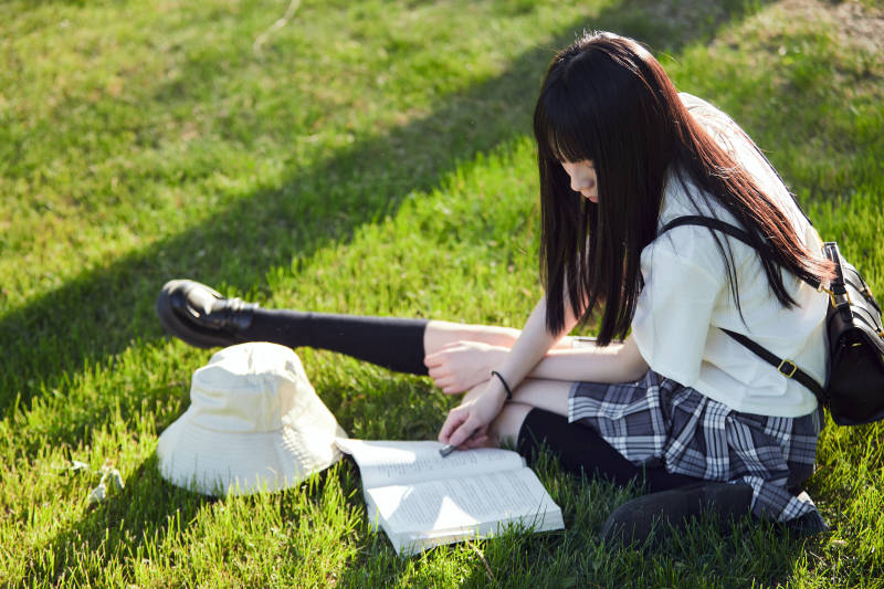 在户外草坪看书学习的女生