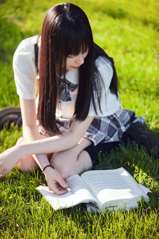 在户外草坪看书学习的女生
