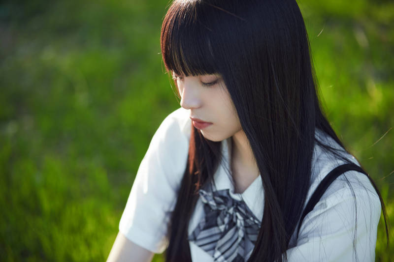 在户外草坪看书学习的女生