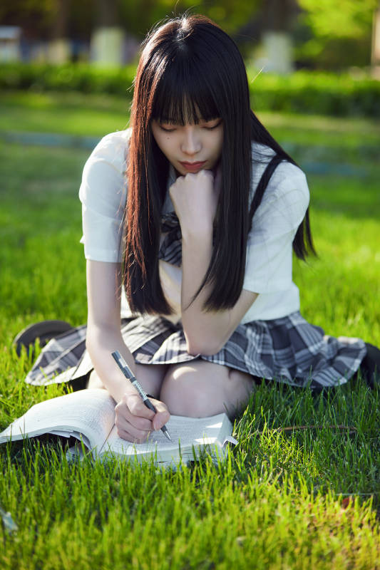 在户外草坪看书学习的女生