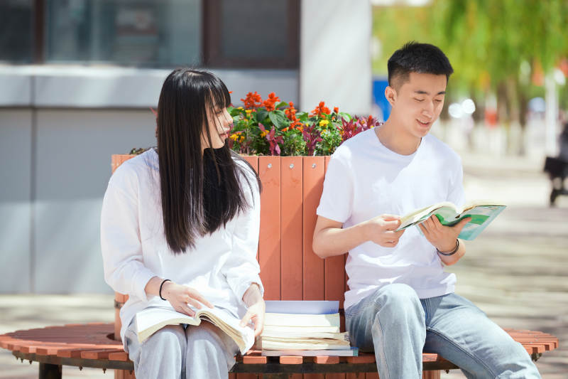 户外校园里读书学习的大学生