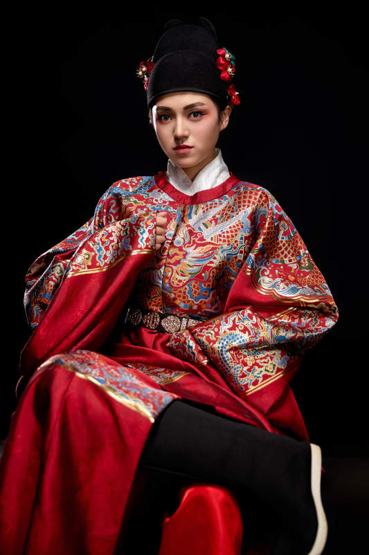 黑色背景下身着明代飞鱼服的青年女性
