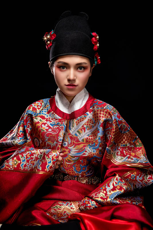 黑色背景下身着明代飞鱼服的青年女性