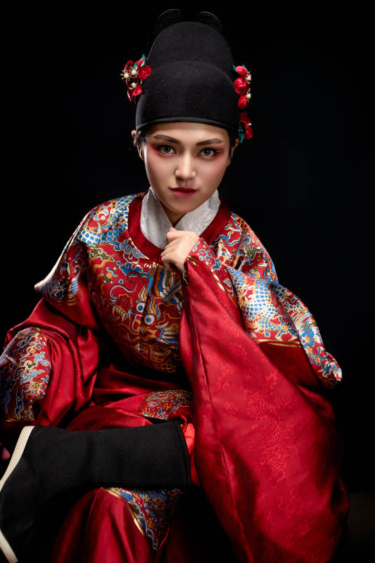 黑色背景下身着明代飞鱼服的青年女性