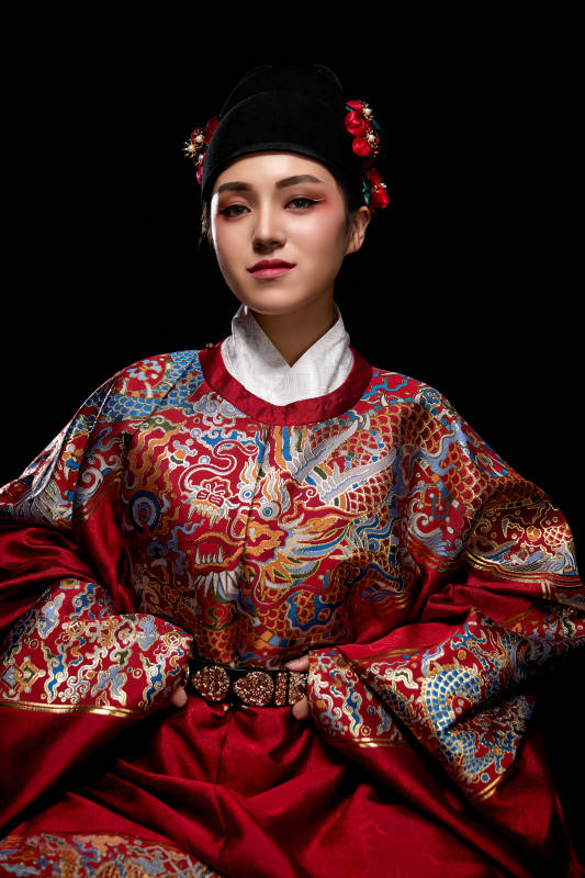 黑色背景下身着明代飞鱼服的青年女性