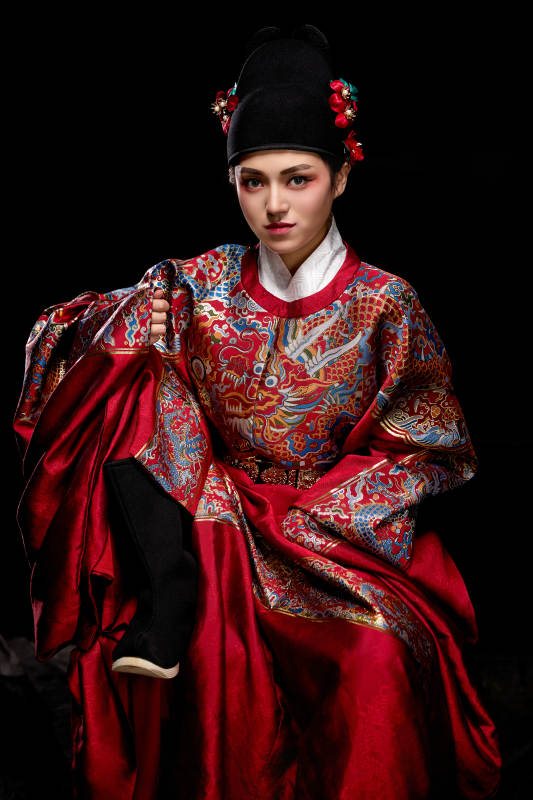 黑色背景下身着明代飞鱼服的青年女性