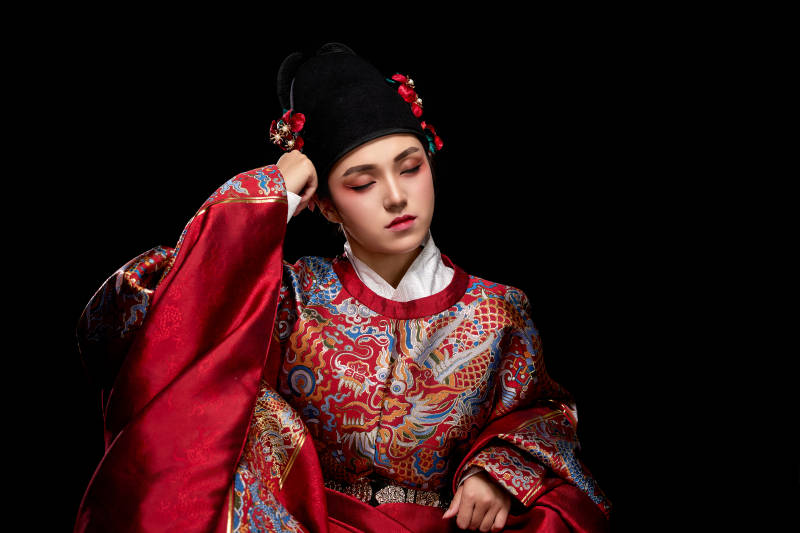 黑色背景下身着明代飞鱼服的青年女性