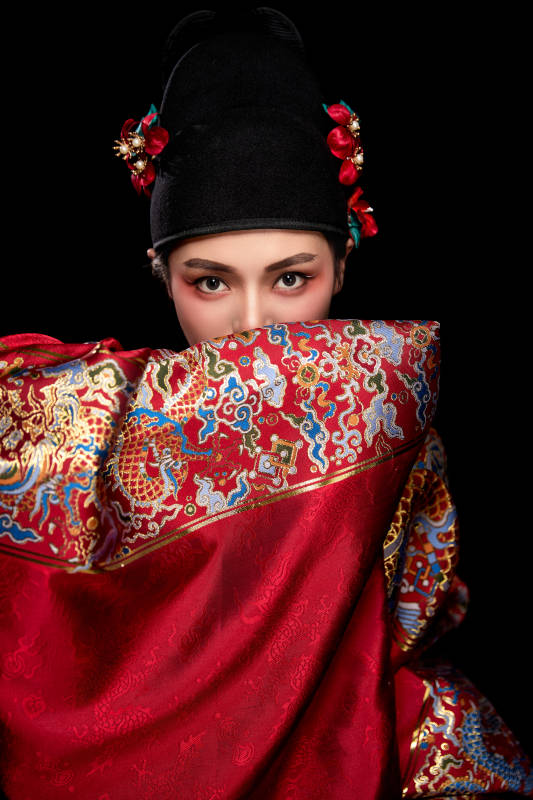 黑色背景下身着明代飞鱼服的青年女性