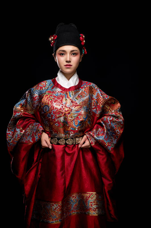 黑色背景下身着明代飞鱼服的青年女性