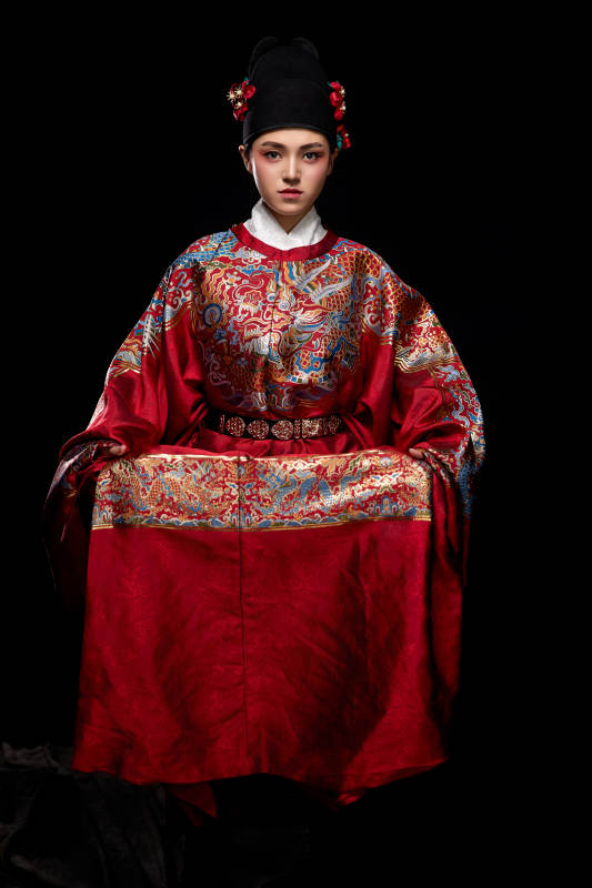 黑色背景下身着明代飞鱼服的青年女性