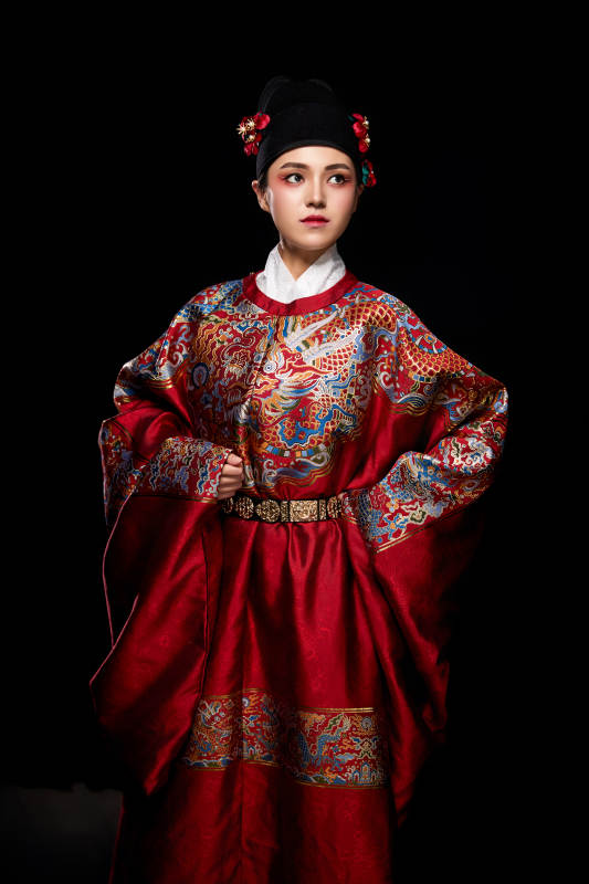 黑色背景下身着明代飞鱼服的青年女性