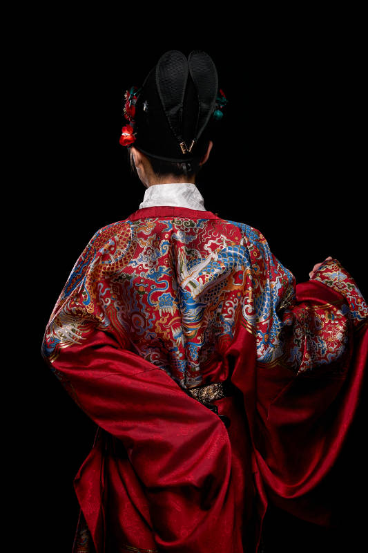 黑色背景下身着明代飞鱼服的青年女性