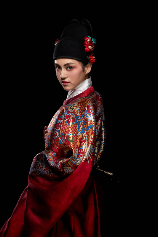 黑色背景下身着明代飞鱼服的青年女性