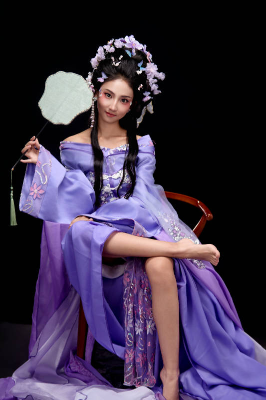 身著簪花仕女裝扮坐在木桌上的東方女性