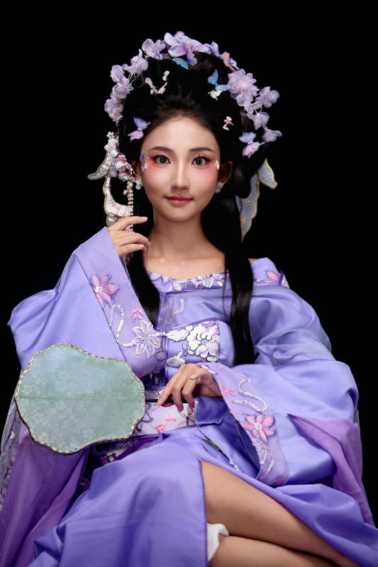 身著簪花仕女裝扮坐在木桌上的東方女性