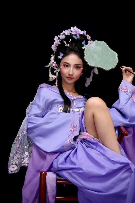 身著簪花仕女裝扮坐在木桌上的東方女性