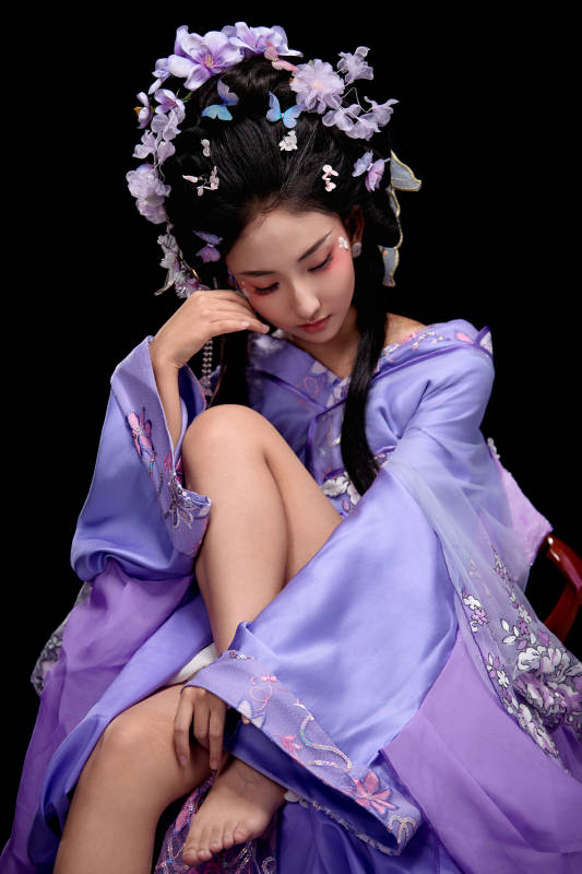 身著簪花仕女裝扮坐在木桌上的東方女性