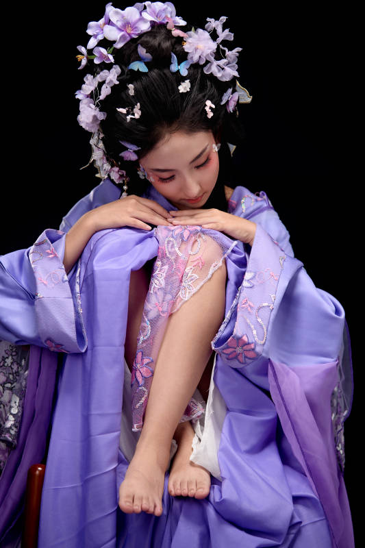 身著簪花仕女裝扮坐在木桌上的東方女性