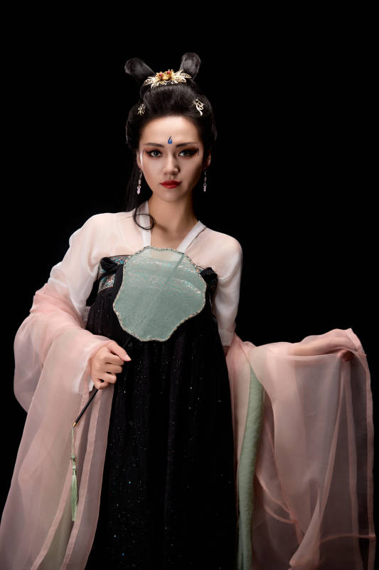 手持轻扇展示唐代服饰妆容造型的东方女性