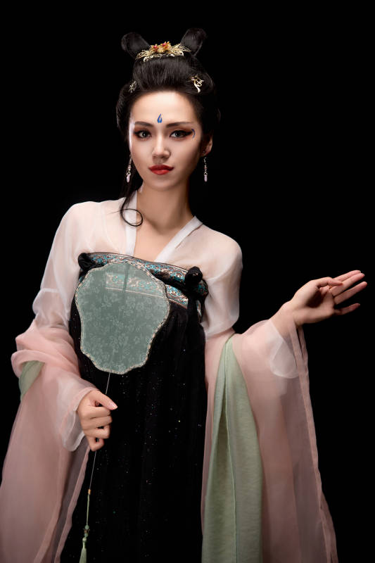 手持轻扇展示唐代服饰妆容造型的东方女性