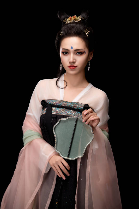 手持轻扇展示唐代服饰妆容造型的东方女性