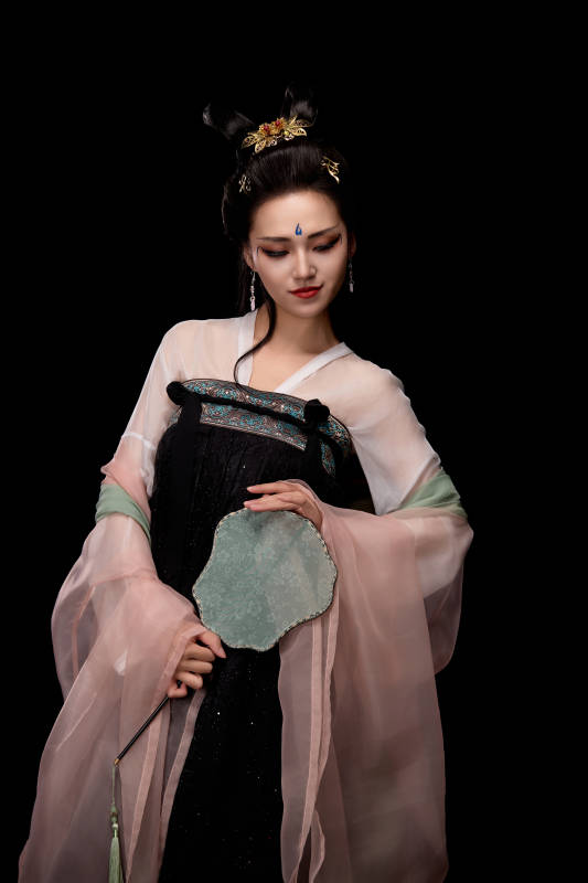 手持轻扇展示唐代服饰妆容造型的东方女性