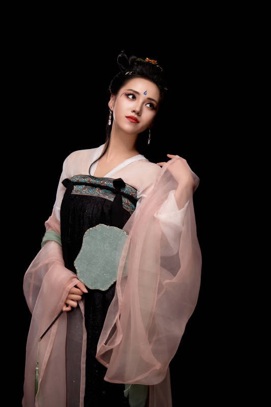 手持轻扇展示唐代服饰妆容造型的东方女性