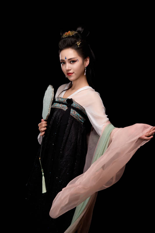 手持轻扇展示唐代服饰妆容造型的东方女性
