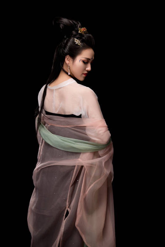 手持轻扇展示唐代服饰妆容造型的东方女性