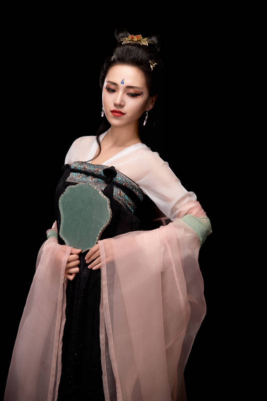 手持轻扇展示唐代服饰妆容造型的东方女性