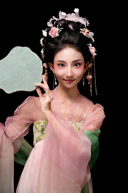 身着唐代宫廷簪花仕女服手持轻扇的女性