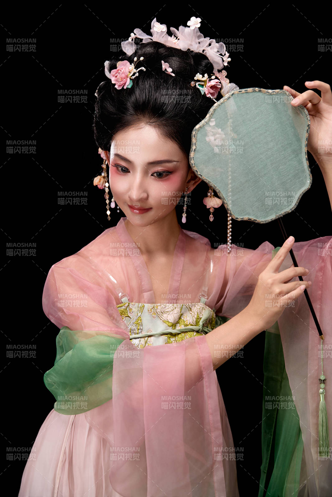 身着唐代宫廷簪花仕女服手持轻扇的女性