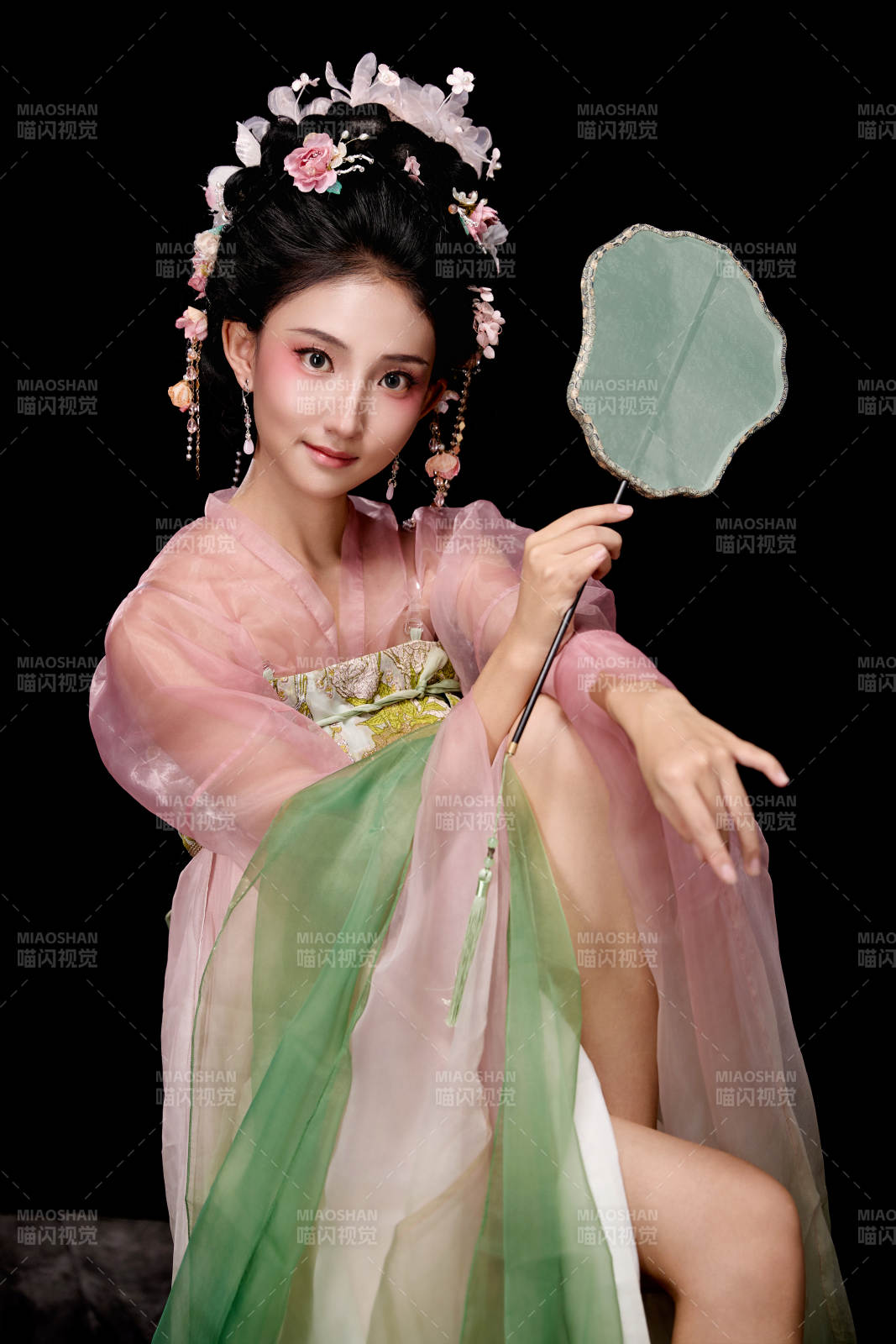 身著唐代簪花仕女服手持輕扇的坐姿女性