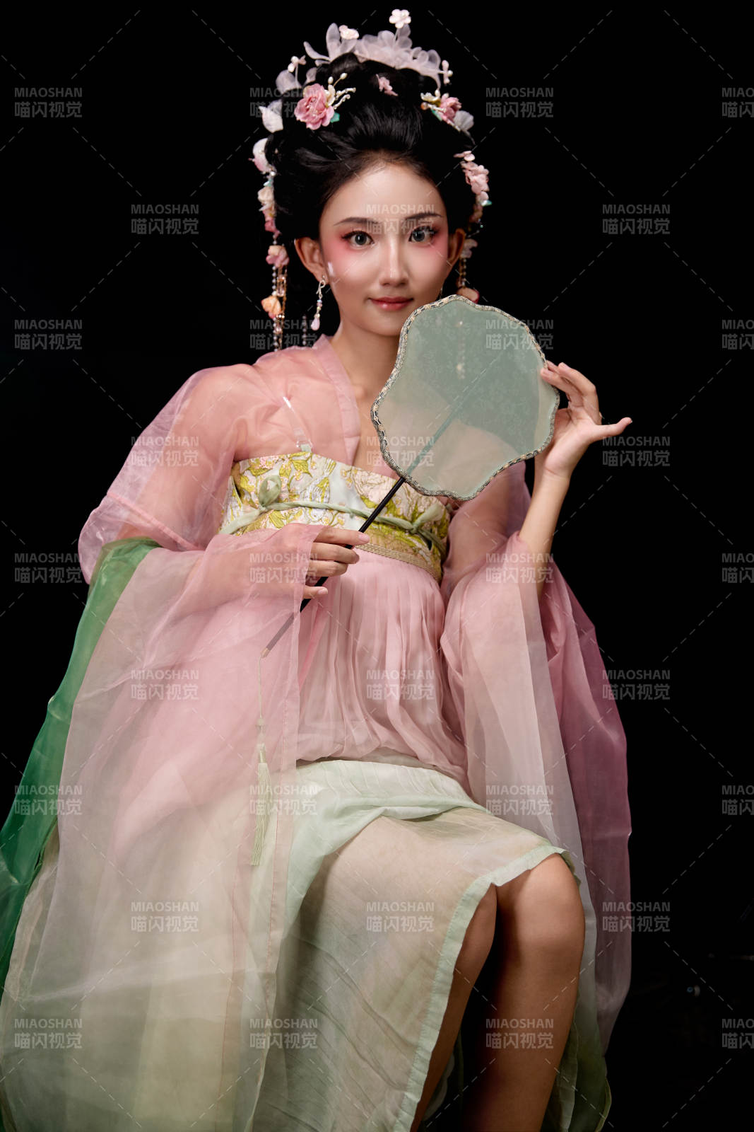 身著唐代簪花仕女服手持輕扇的坐姿女性