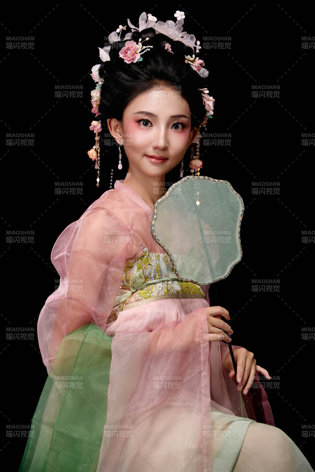 身著唐代簪花仕女服手持輕扇的坐姿女性